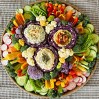 Crudité platter with fresh vegetables, radishes, cucumbers, snap peas, broccoli, and assorted dips