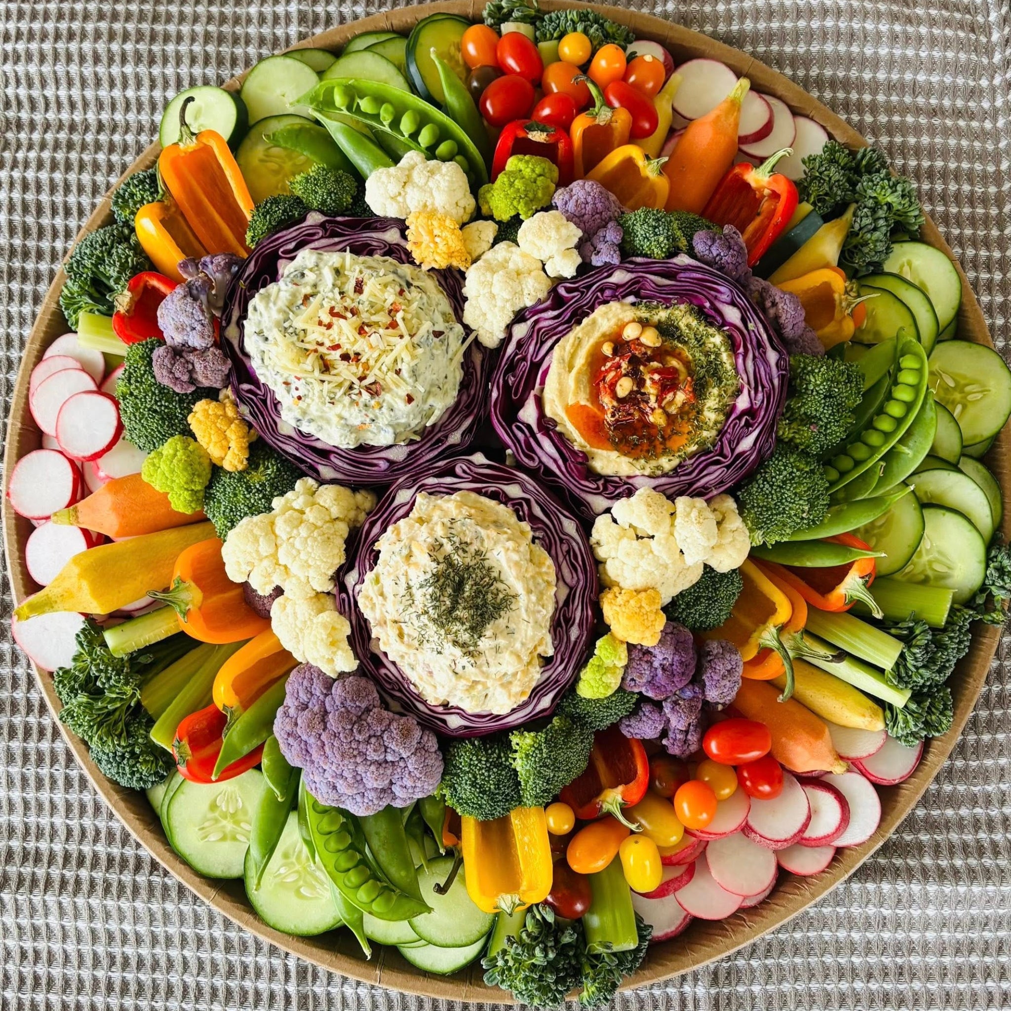 Crudité platter with fresh vegetables, radishes, cucumbers, snap peas, broccoli, and assorted dips