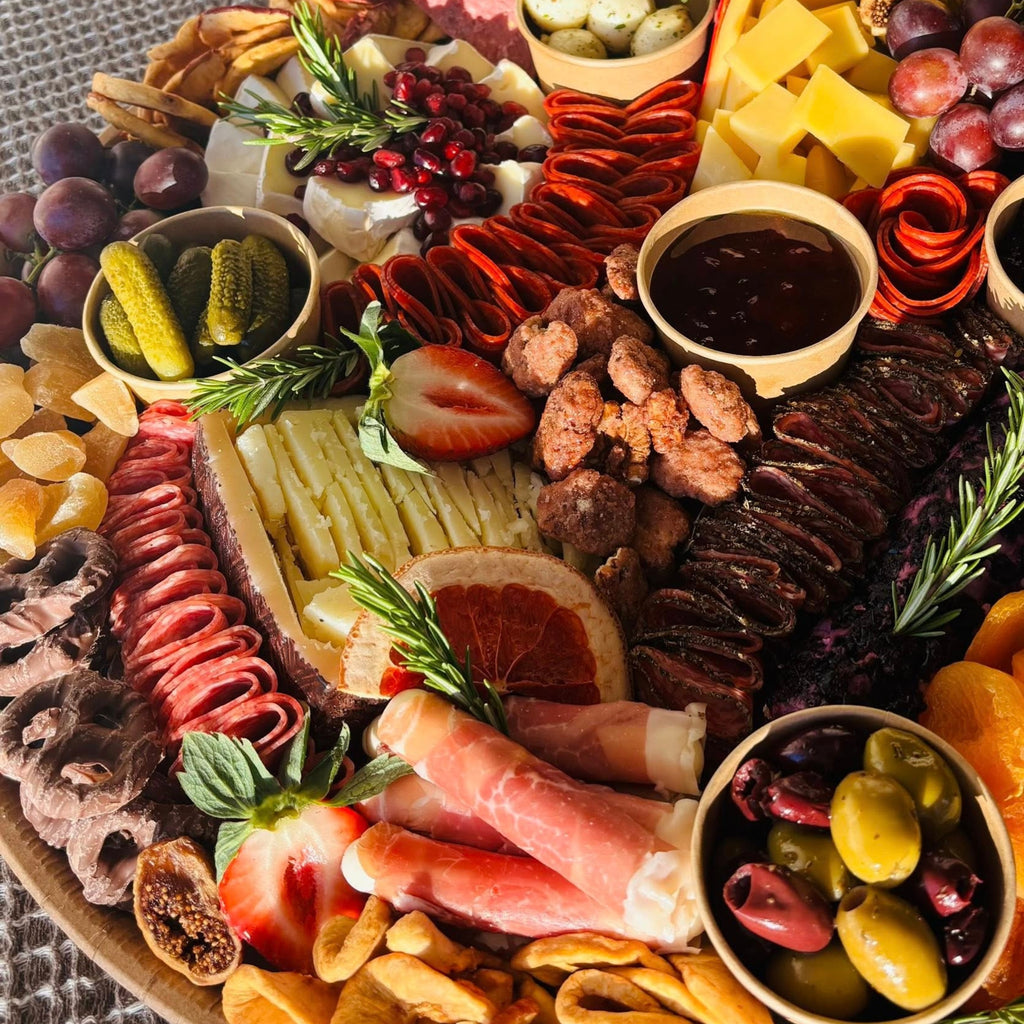 Charcuterie board with cheeses, cured meats, olives, pickles, nuts, jam, and fresh fruit