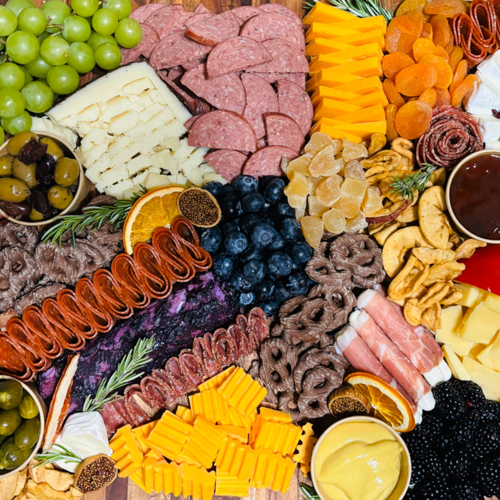 Charcuterie board with sliced meats, cheddar and white cheese, grapes, blueberries, olives, dried fruit, nuts, and honey, Dayton Ohio catering