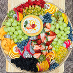Fruit platter with green grapes, strawberries, blueberries, raspberries, melon dip, and chocolate-dipped fruit