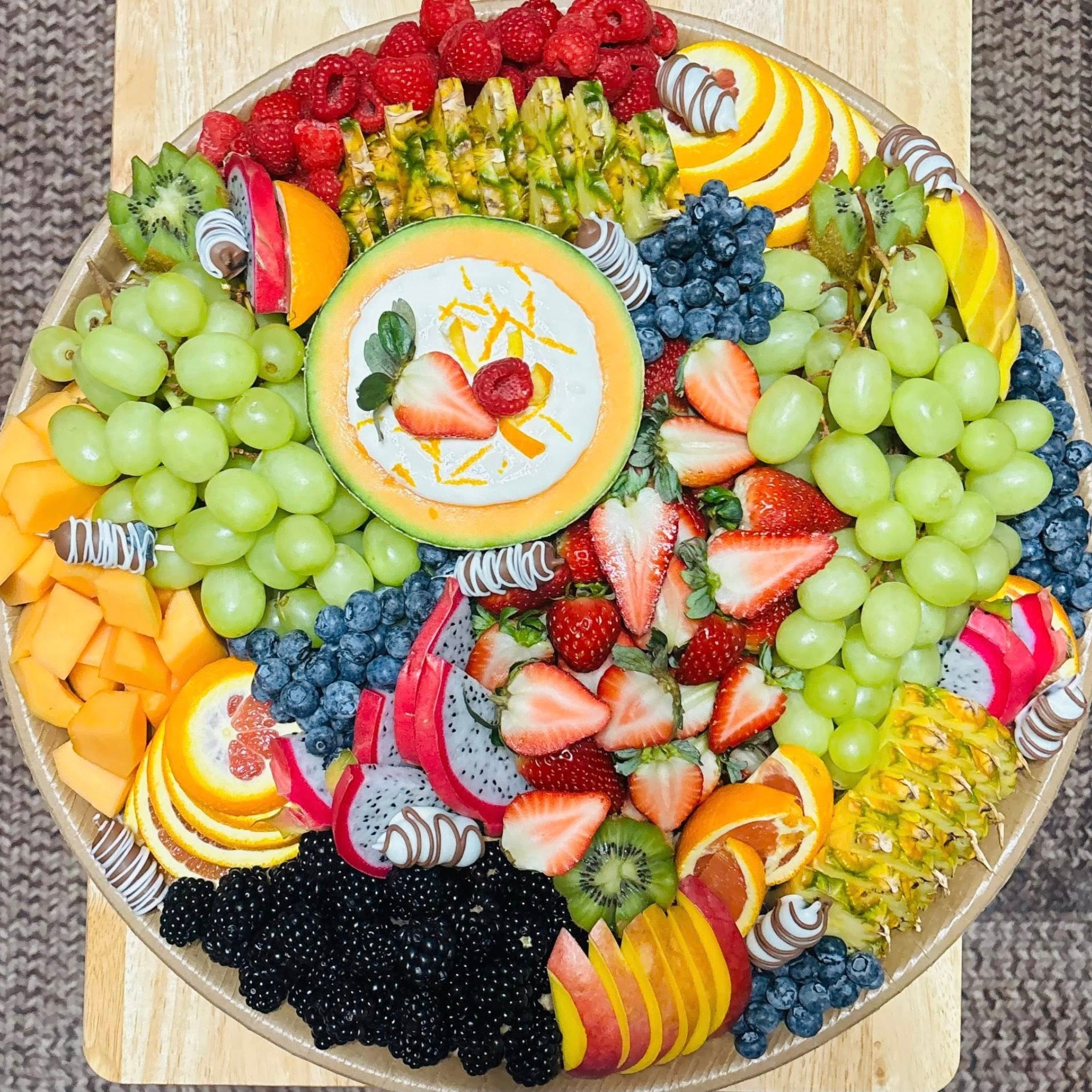Fruit platter with green grapes, strawberries, blueberries, raspberries, melon dip, and chocolate-dipped fruit