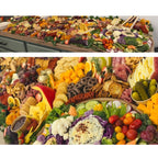 Full grazing table spread with charcuterie, cheeses, fresh fruit, crackers, dips, and vegetable platters